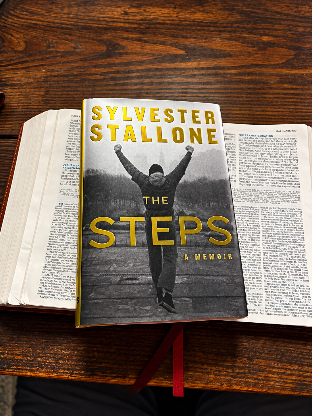 Sylvester Stallone’s The Steps memoir resting on an open Bible on Chuckie’s wooden desk