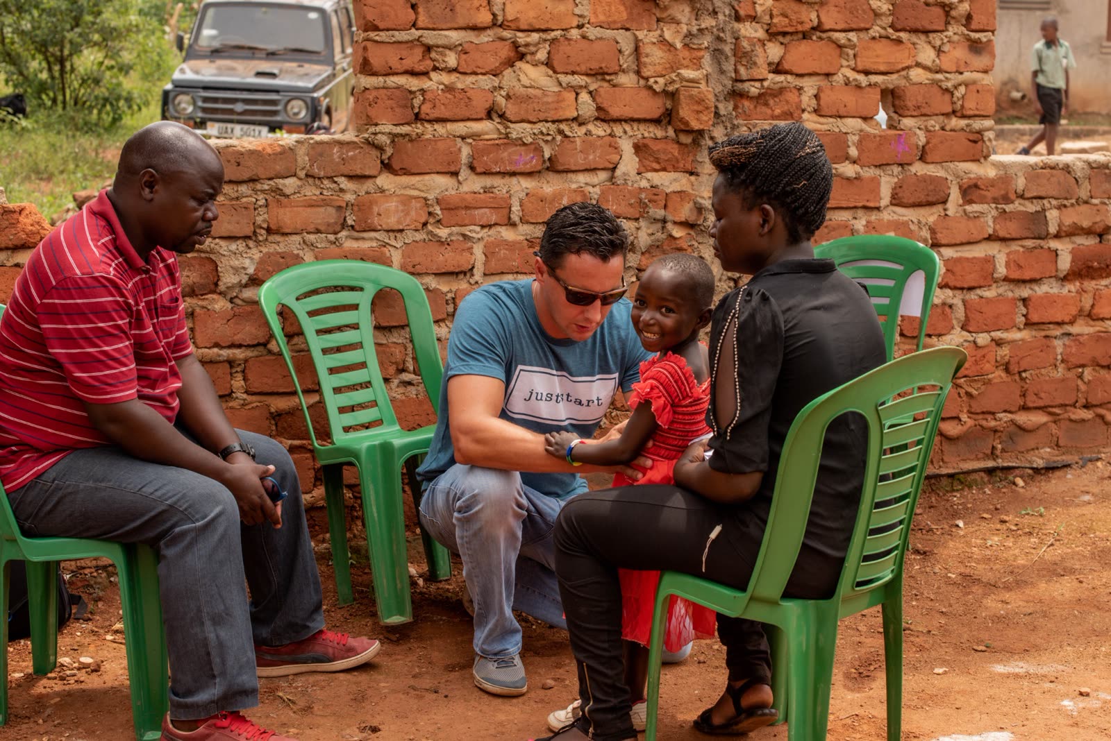 Chuckie caring for a child with local leaders in Uganda