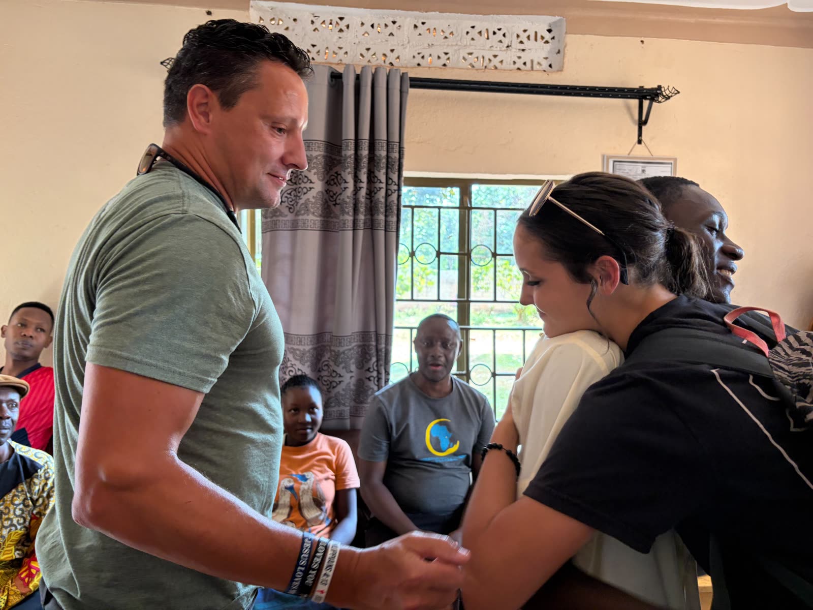 Chuckie and Amanda serving and embracing a woman during the Uganda mission