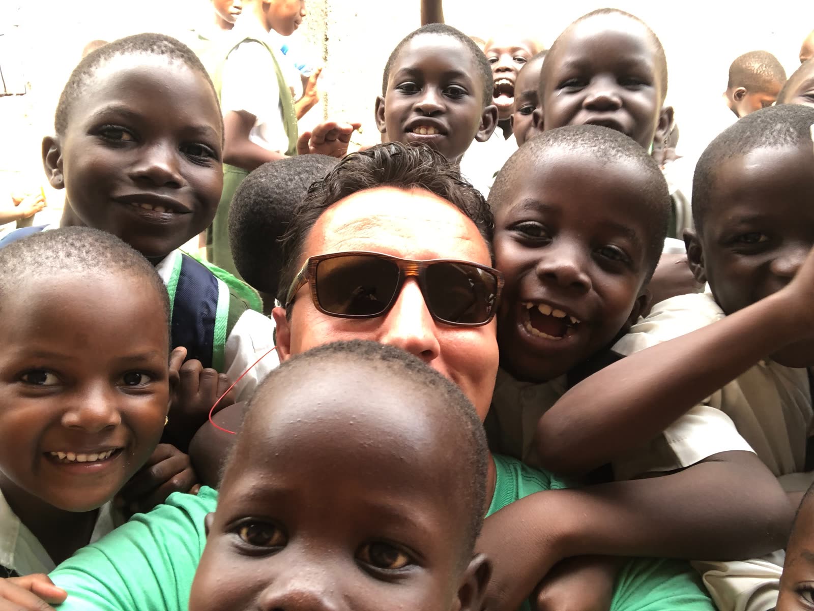 Chuckie surrounded by smiling children during mission work in Uganda